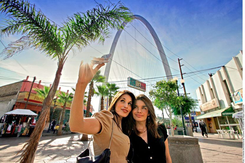 Dos mujeres se toman una foto enfrente de un letrero que dice "Tijuana".