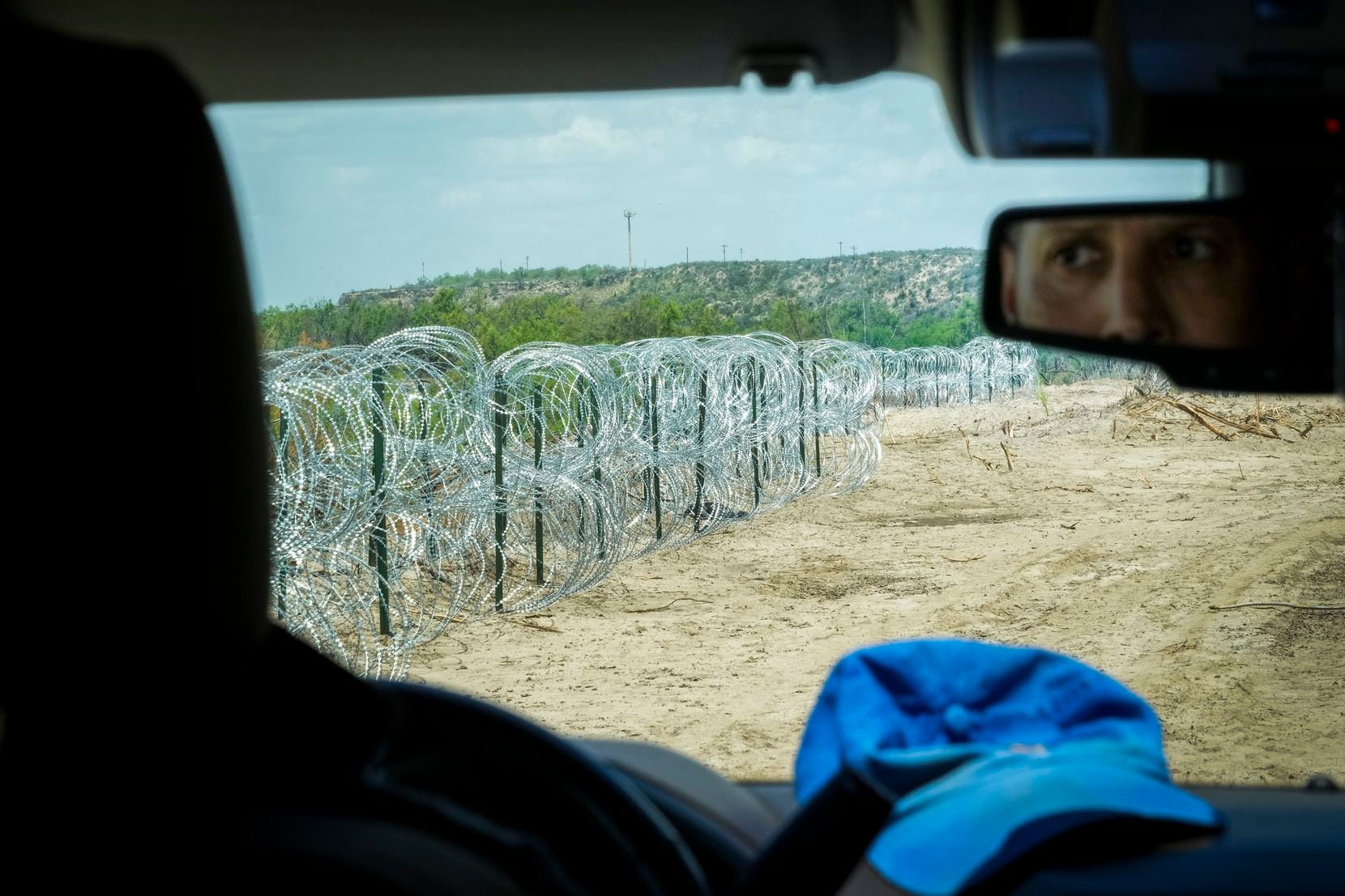 Poncho Nevárez drives along a stretch of concertina wire on his property along the Rio...
