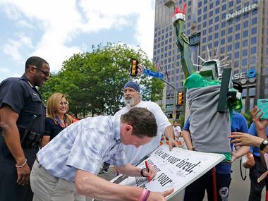 Dallas County Judge Clay Jenkins signs a poster during the Mega March, which started at the...