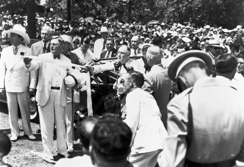 President Franklin D. Roosevelt seated in an automobile as he pulls a ribbon to unveil the...