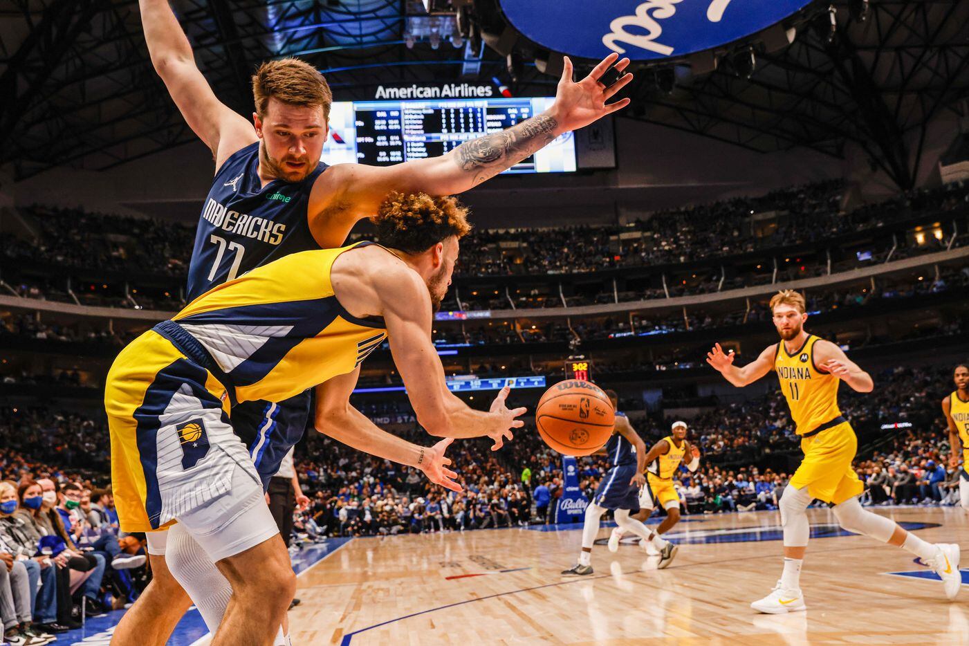 Indiana Pacers guard Chris Duarte (3) makes a pass to forward Domantas Sabonis (11) through Dallas Mavericks guard Luka Doncic (77) during a game at the American Airlines Center in Dallas on Saturday, January 29, 2022.