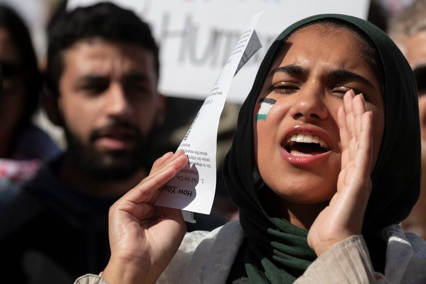 A young woman, not identified by name, wears a small Palestinian flag on her face as she...