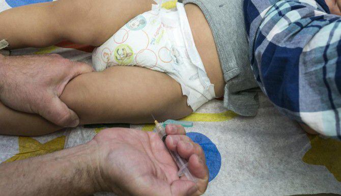 Un pediatra utiliza una jeringa para vacunar a un niño de un año. Un estudio revela que cada...