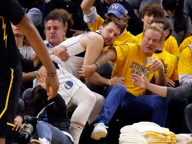 Dallas Mavericks guard Luka Doncic (77) ends up in the lap of Golden State Warriors fans...