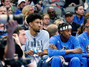 Dallas Mavericks forward Christian Wood (left) sat on the bench in street clothes with an...