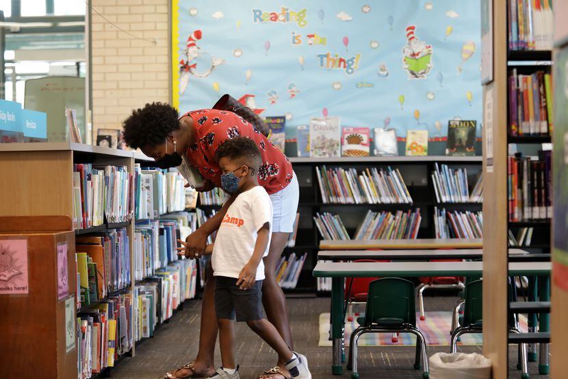 Whitney Lewis and 4-years-old Carter Lewis look through the available books at the North Oak...