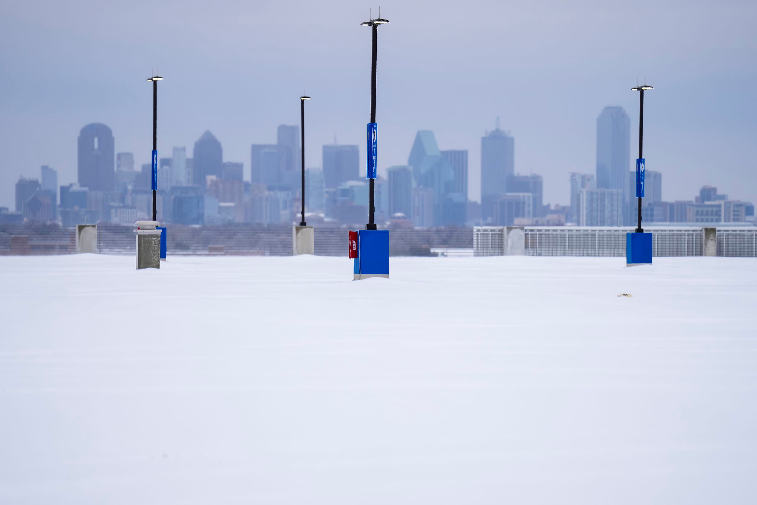 The downtown skyline is seen over the snow-covered top parking level of a garage at Dallas...