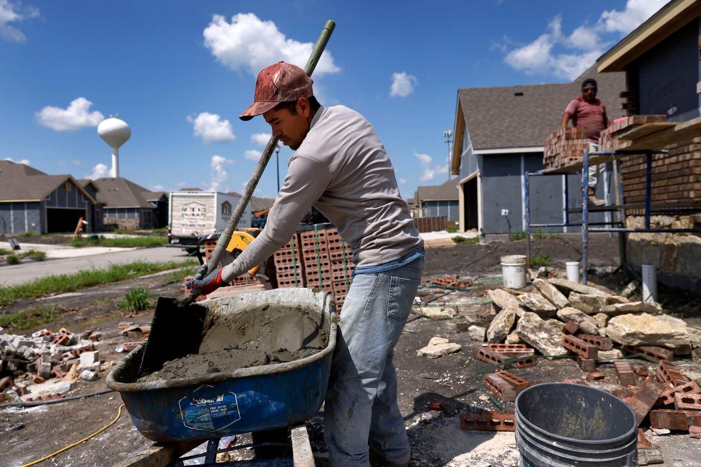 Construction worker Clemente Trejo mixes a wheelbarrow full of concrete for brick laying on...