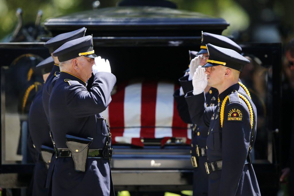 Dallas police Honor Guard members salute before removing the flag-draped casket of slain...