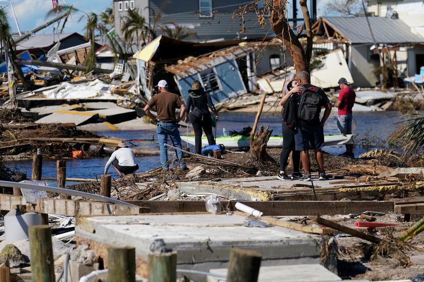 Gente de pie en el puente destruido a Pine Island mientras contemplan los daños causados por...