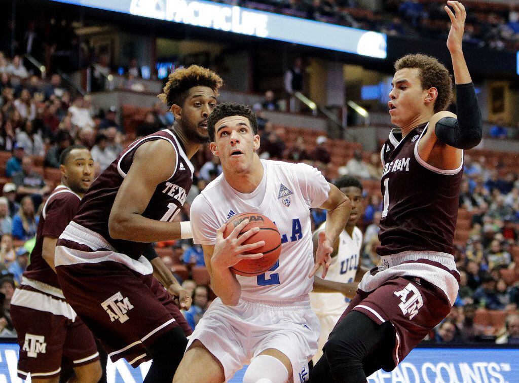 UCLA's Lonzo Ball drives to the basket under pressure from Texas A&M's Tonny Trocha-Morelos,...