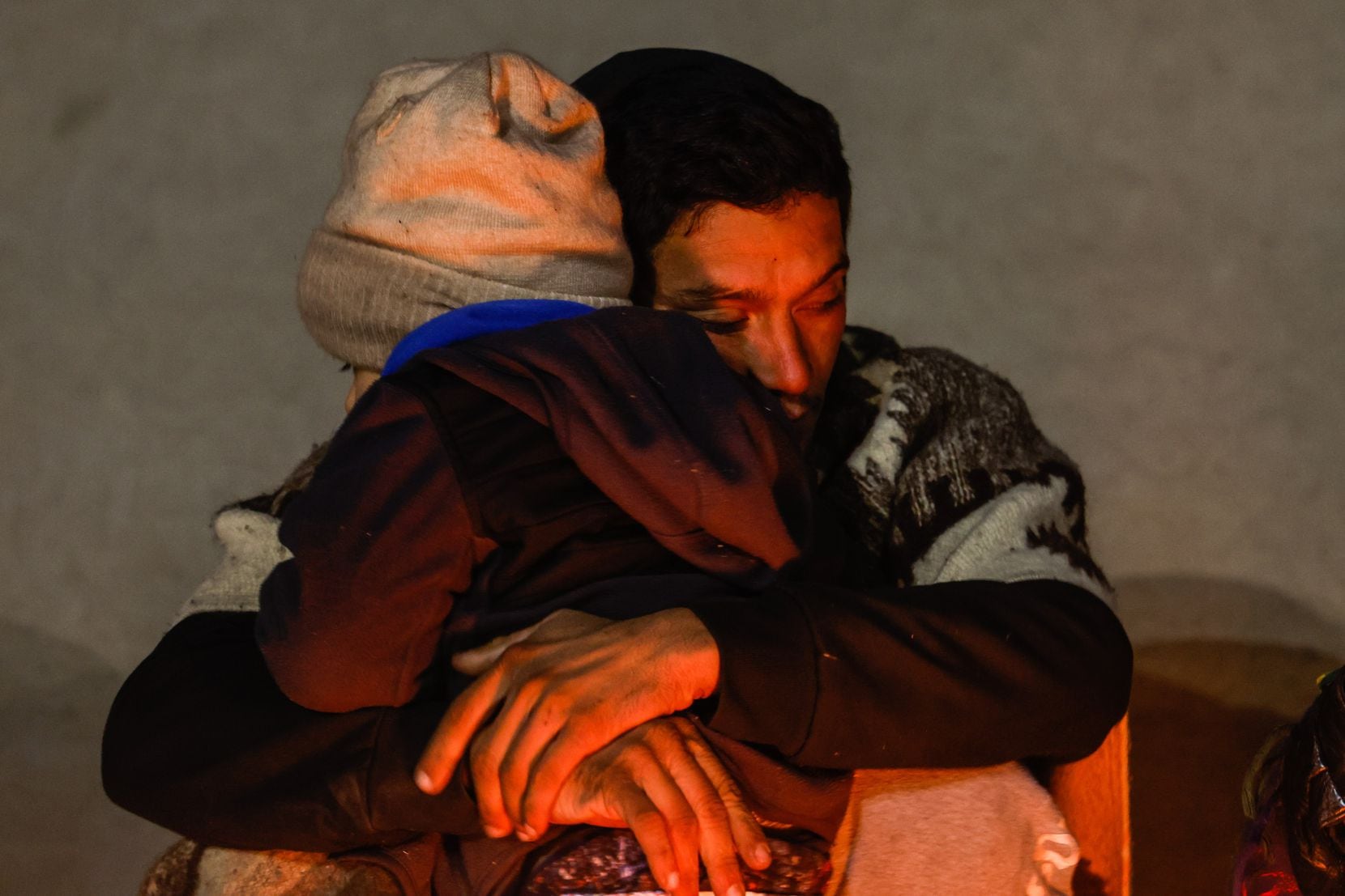 Luis Fernando, from Venezuela, hugs his son Luis Leandro, 3, in front of a a small campfire...