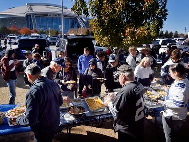 Dallas Cowboys fans dig into a Thanksgiving feast during at tailgate party outside of AT&T...