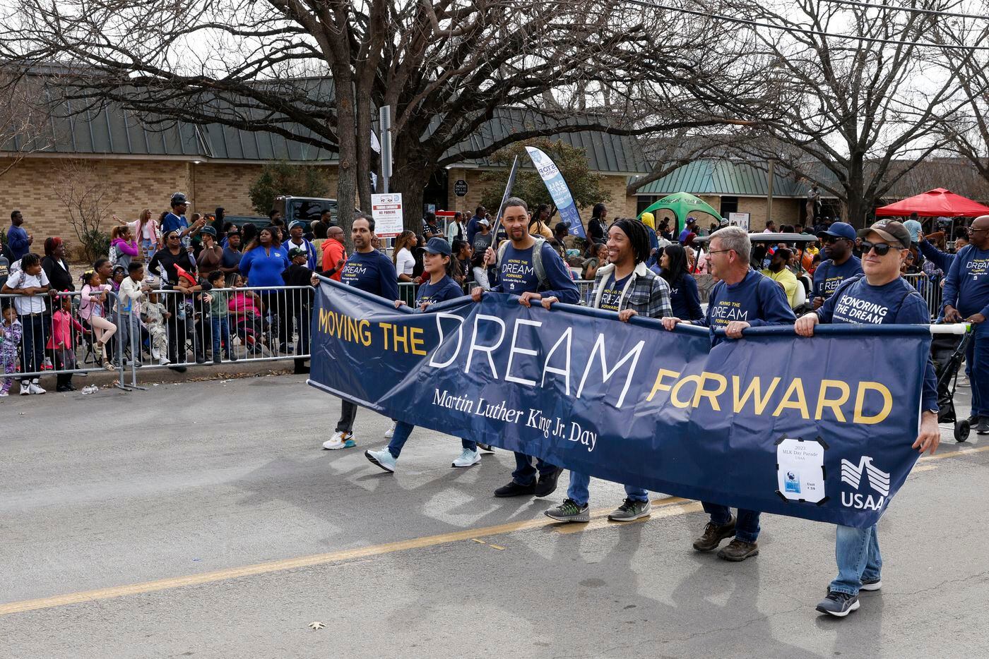 People with USAA walk with a banner during the Martin Luther King Jr. Day Parade in Dallas,...