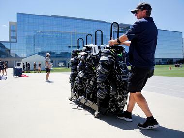 Dallas Cowboys equipment manager Mike McCord pulls a rack of shoulder pads after players...