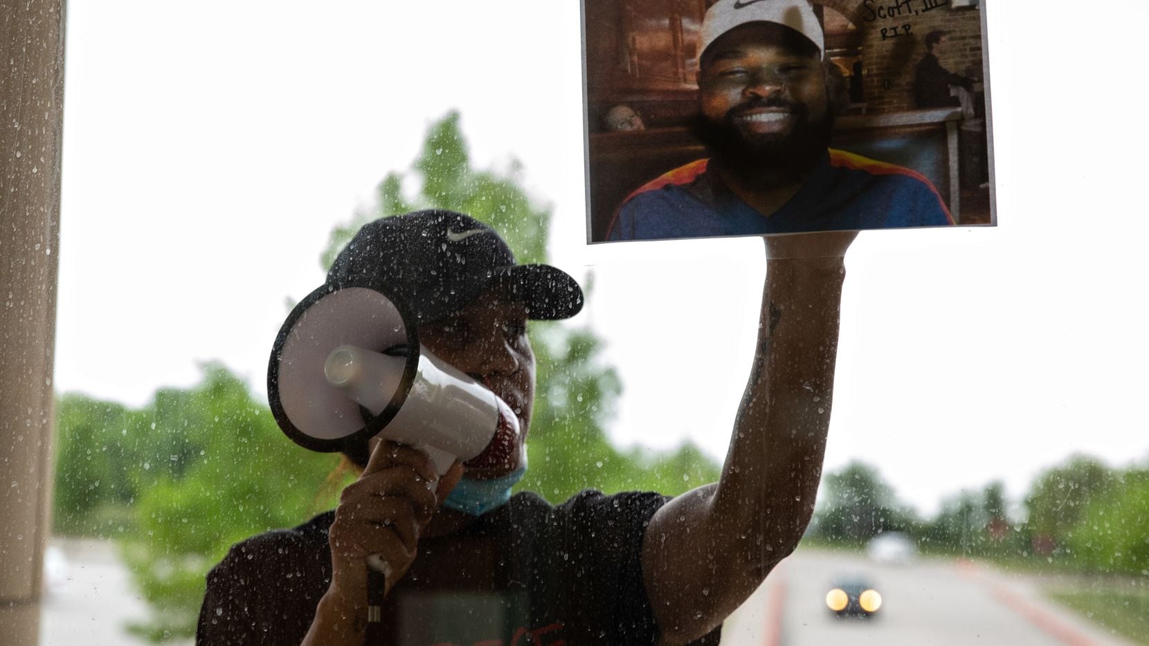 Renee White presses a photo of Marvin Scott III on the windows of the Collin County Courthouse while demanding the officers present arrest the officers involved in Scott's in-custody death after a press conference on April 28, 2021.