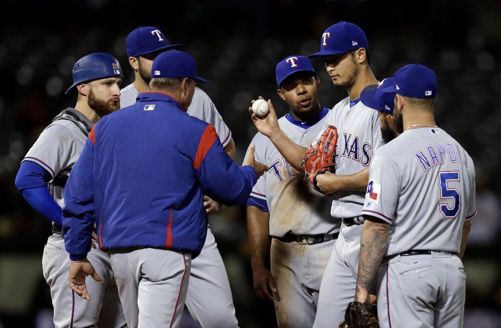 Texas Rangers pitcher Yu Darvish, second from right, hands the ball to manager Jeff Banister...
