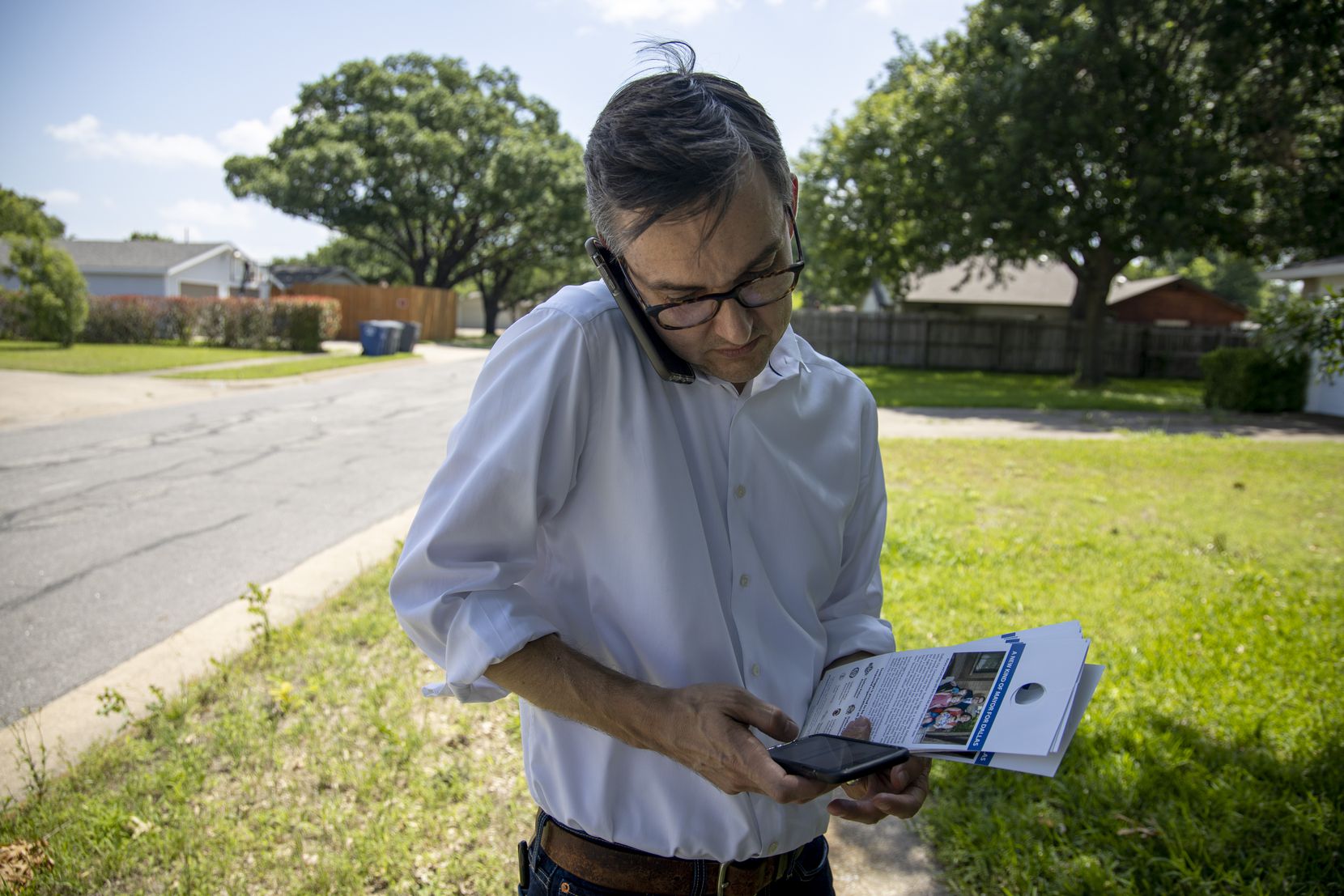 Scott Griggs, a four-term Dallas City Council member and mayoral candidate, answers a call while checking a voter database on his other smartphone as he block-walks in a Lake Highlands neighborhood on Friday, May 24. (Shaban Athuman/Staff Photographer)