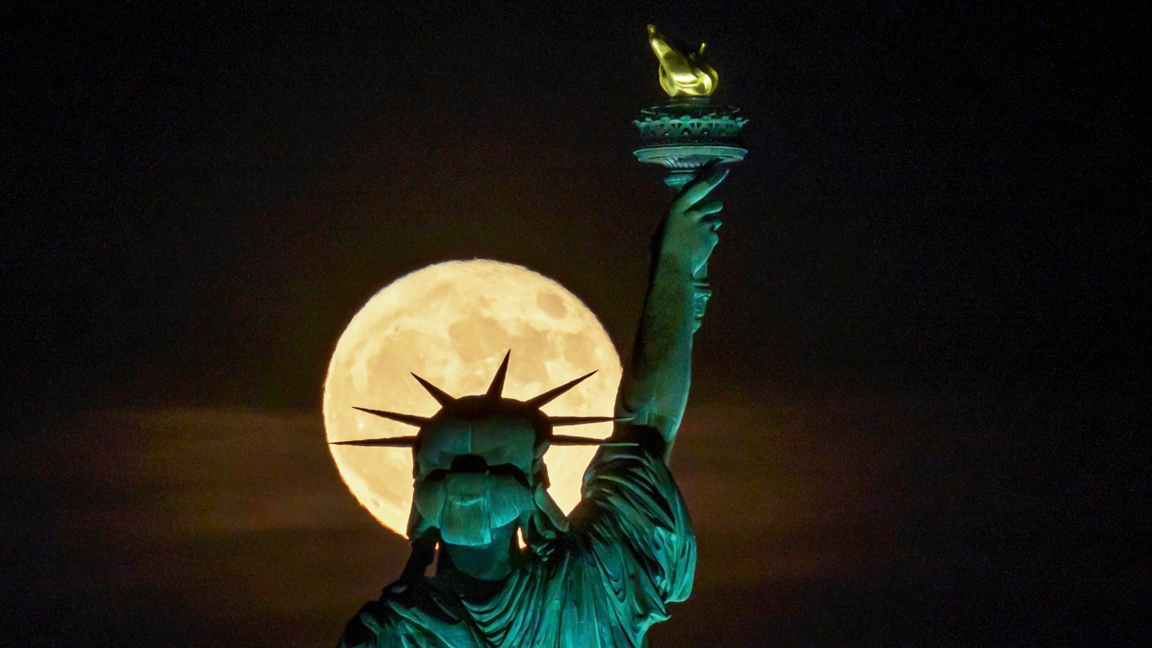 The Strawberry Supermoon rises in front of the Statue of Liberty in New York, June 14, 2022....