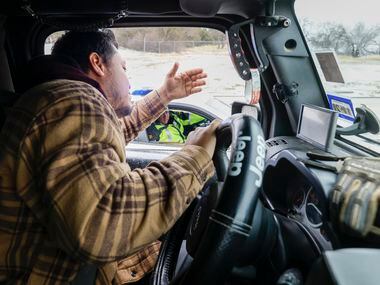 Angel Muniz talks with a Dallas police officer before towing a pair of stuck semi-trucks...