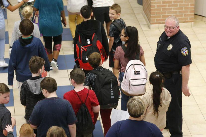 El policía Chris Golden sonríe a los estudiantes que llegan a la cafetería de la secundaria...