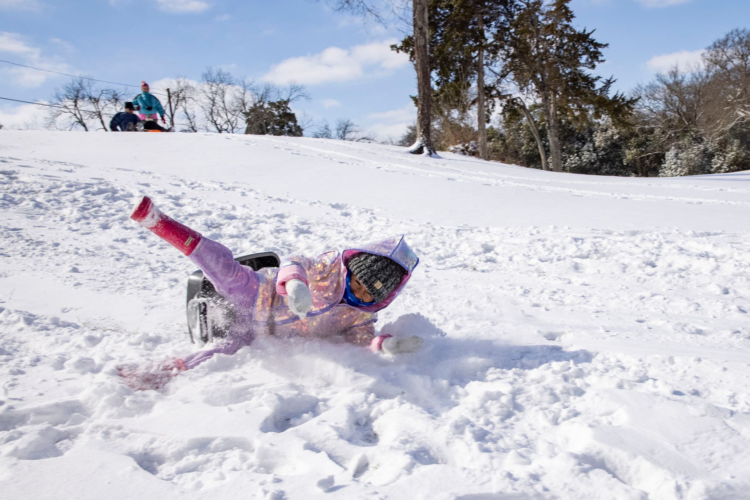 Mia Donjuan, 4, wipes off of her pan as she slides down a hill in the Dallas Elmwood...