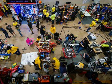 Don Prier (bottom, center) works with his Spring Woods High School robotics team in the pits...