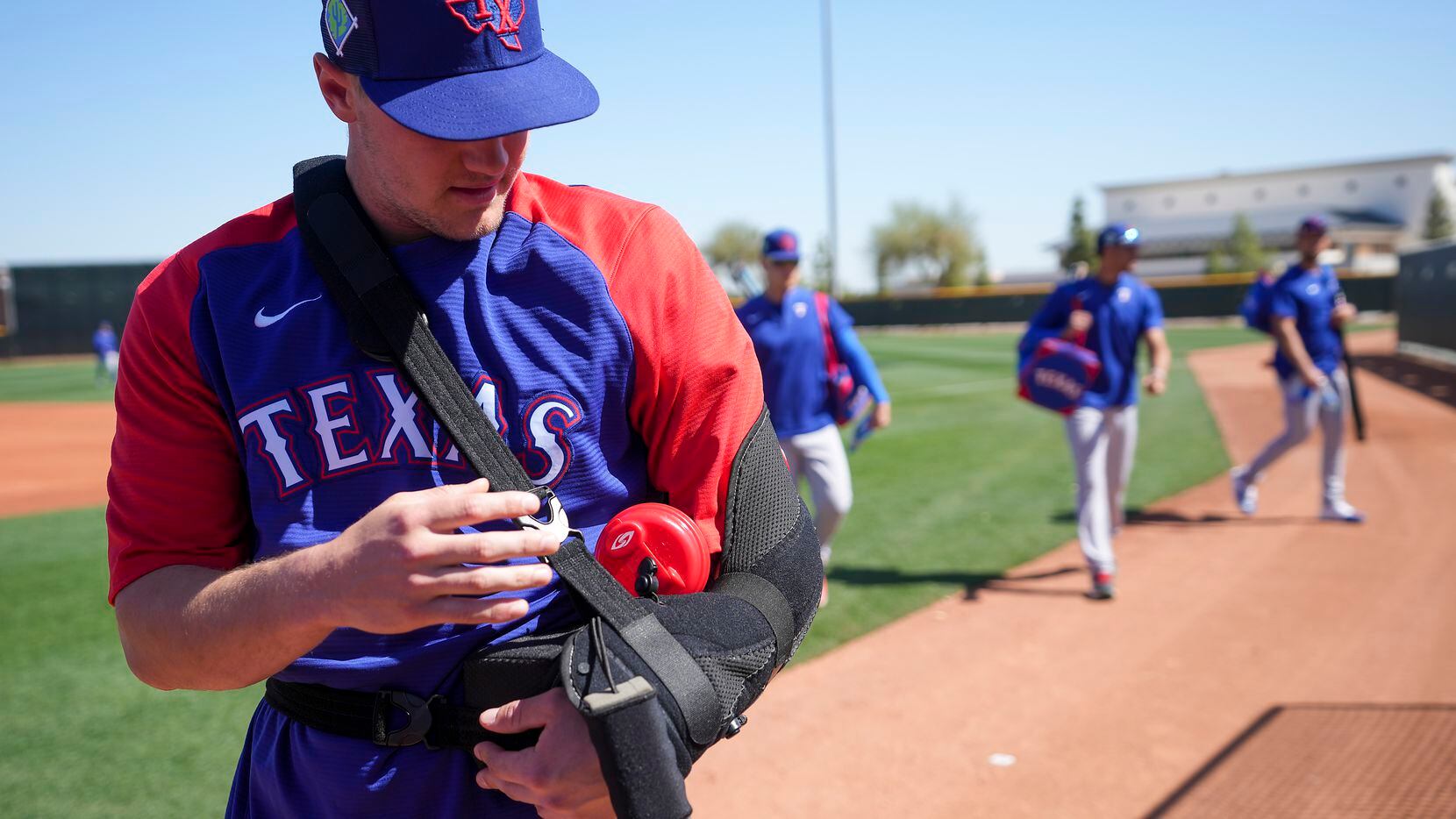 Texas Rangers infielder Josh Jung wears a sling  during a spring training workout at the...