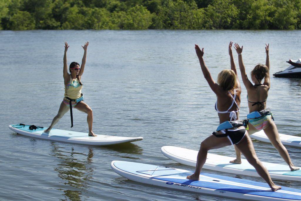 Instructor Jenn Bodnar leads a stand-up paddleboard yoga class at DFW Surf on Lake Lewisville.