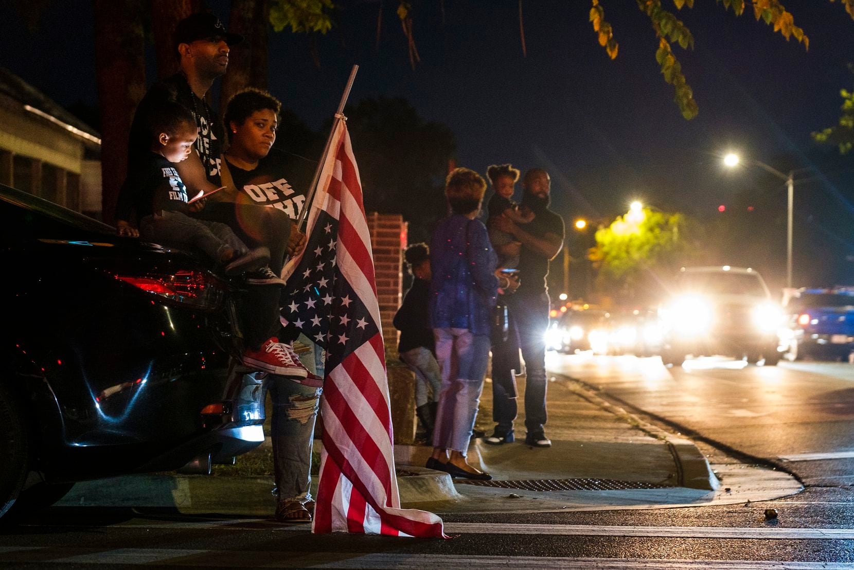 Protestors, including a man carrying an upside-down American flag, gathered outside the...