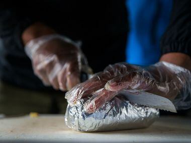 Jessie Washington, Brunchaholics owner and chef, cuts a "Soul Food Burrito" in half at his...