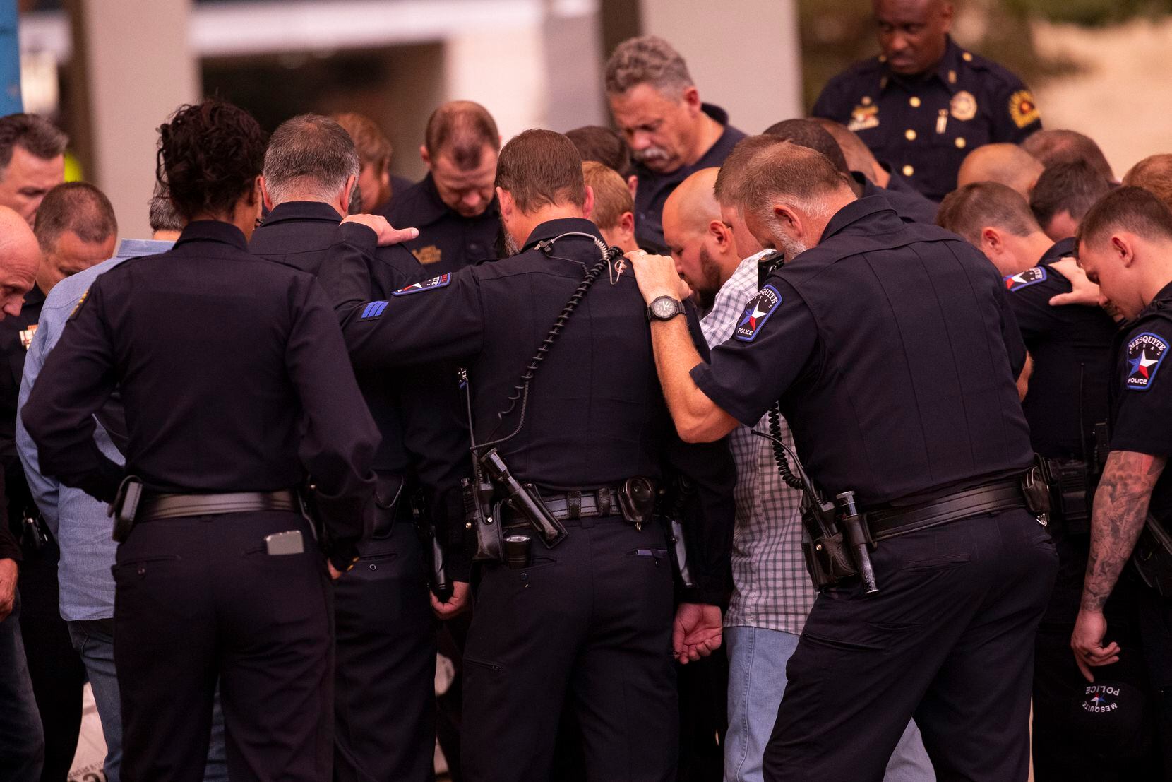 Dallas and Mesquite police officers bow their heads in prayer outside of Baylor University Medical Center.