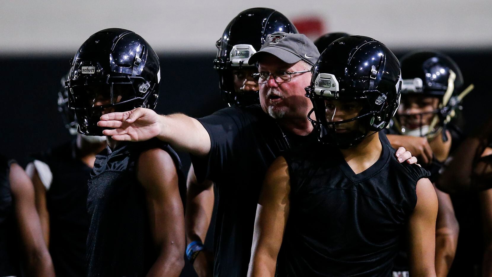 Euless Trinity coach Chris Jensen gives instructions to his players during a varsity practice at Euless Trinity High School, Monday, August 9, 2021.