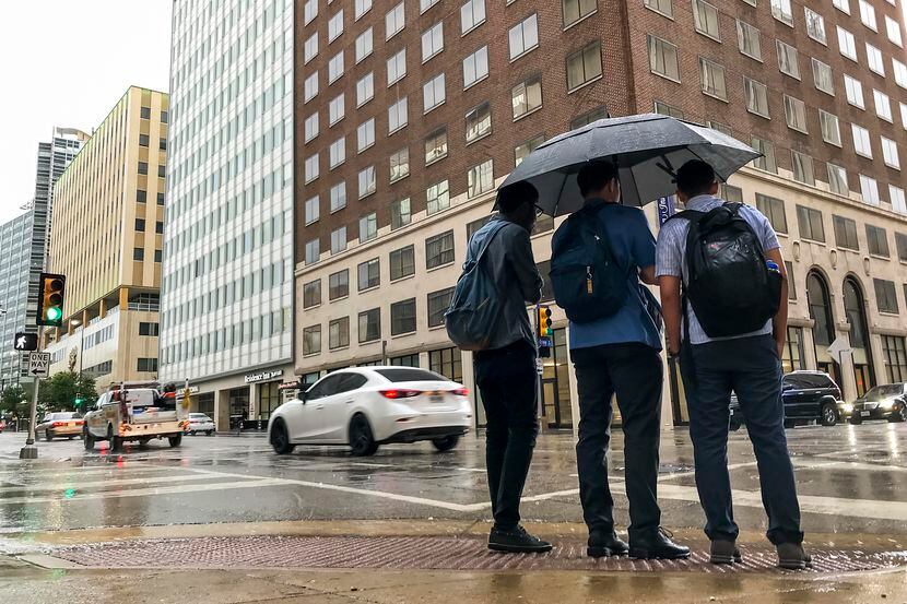 Pedestrians take cover from the rain as a thunderstorm rolls through downtown Dallas. in 2018.