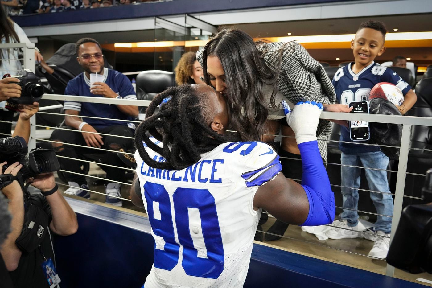 Dallas Cowboys defensive end Demarcus Lawrence (90) kisses his wife Sasha after handing the Sunday Night Football Player of the Game Ball to his son Damari, 7, as he leaves the field following a victory over the Washington Football Team in an NFL football game at AT&T Stadium on Sunday, Dec. 26, 2021, in Arlington. The Cowboys won the game 56-14.