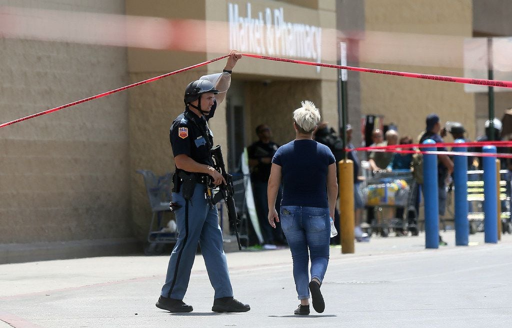 An employee crosses into the crime scene following a shooting at a Walmart in El Paso,...