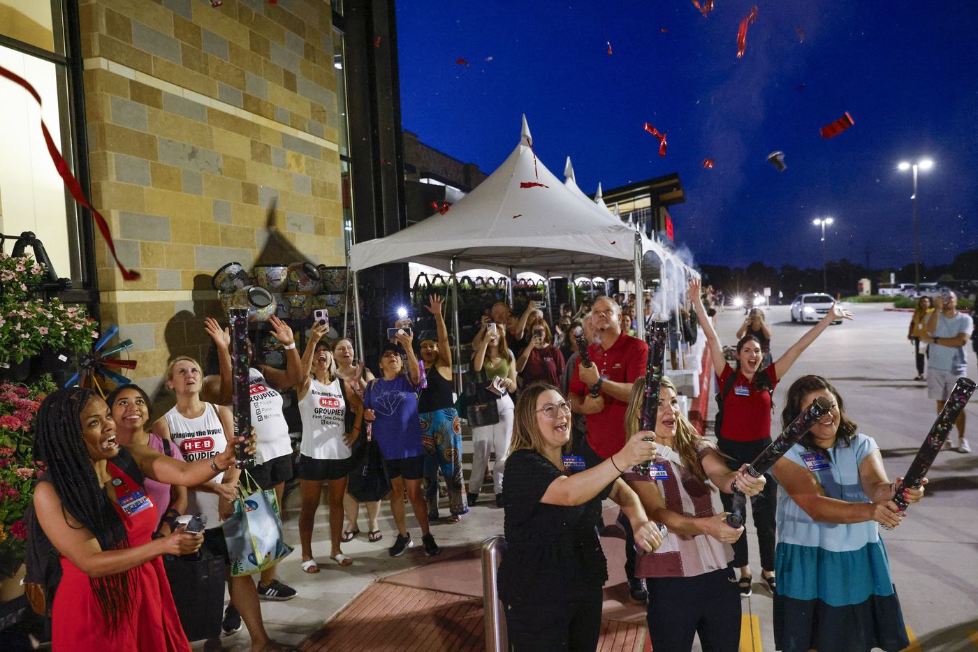 Customers and employees cheer as confettis explode during the opening day of H-E-B on...