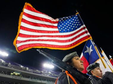 A stiff wind blows the flags as the color guard stands on the field before the Armed Forces...
