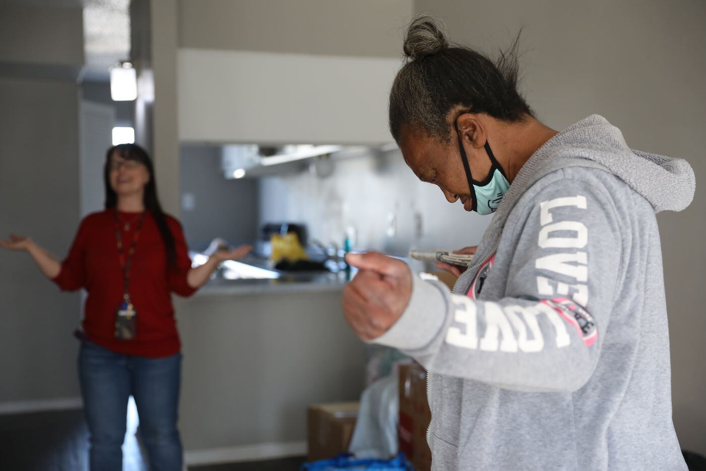 Faith Bartes (left), staff member at The Bridge Homeless Recovery Center, leads Patricia Freeman in prayer, blessing Freeman's new apartment in southern Dallas on November 19, 2021. (Liesbeth Powers/Special Contributor)