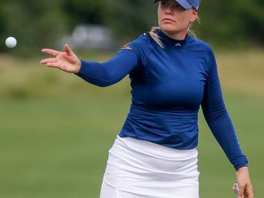 Professional golfer Matilda Castren tosses a ball to her caddie on the No. 18 green during...
