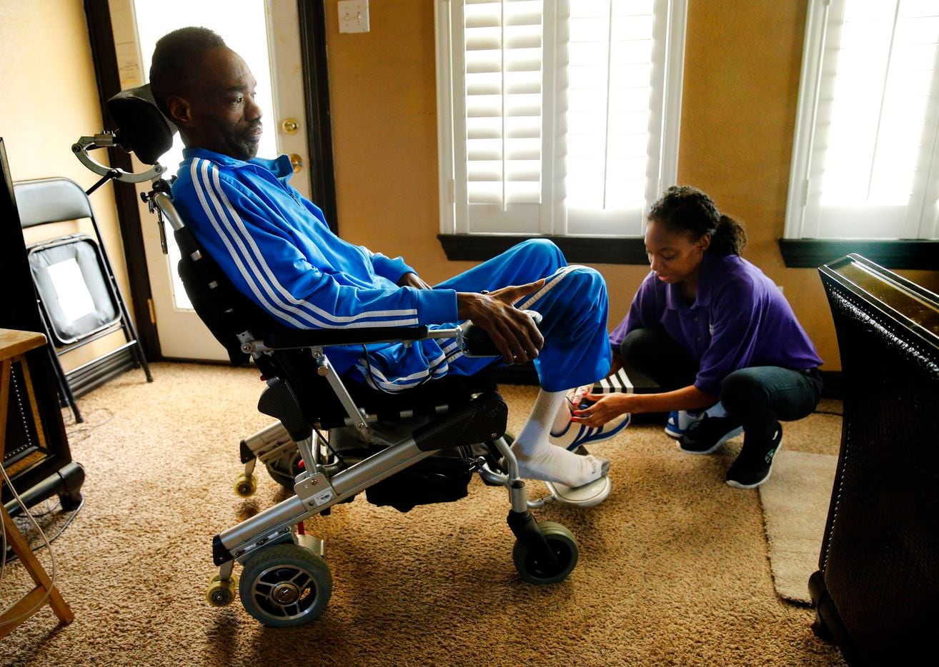 Dressed in one of his colorful Adidas track suits,  former NFL player Rickey Dixon   gets ready for the day with the assistance of his daily care giver Shanika Glover at his Red Oak, Texas home, Friday, April 7, 2017. (Tom Fox/The Dallas Morning News) 