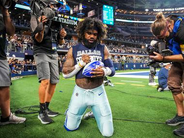 Dallas Cowboys running back Ezekiel Elliott autographs a football for a fan as he leaves the...