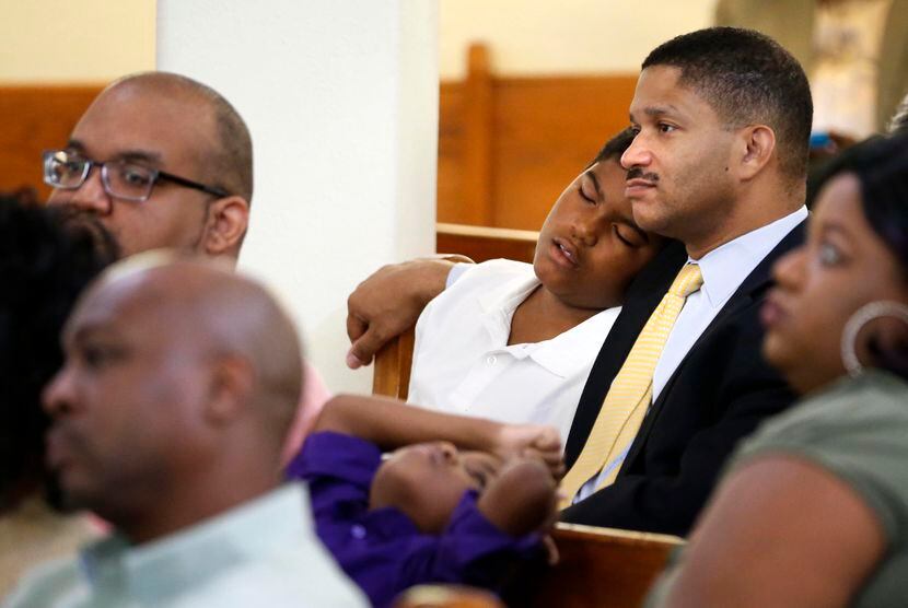 Christopher Waters falls asleep on his father James' shoulder at St. Paul United Methodist...