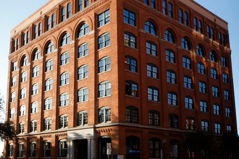 Cars drive past the Sixth Floor Museum, which was once the book depository building as...