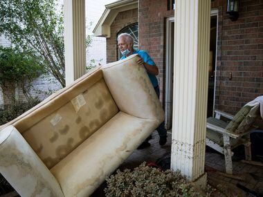 Steve Thompson pushes a flood damaged couch out of his house in the aftermath of Hurricane...