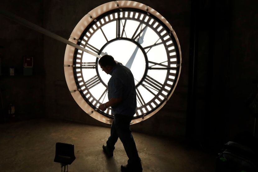 Historic clock restoration specialist Chuck Roeser of Lockport, N.Y., ducks under one of...