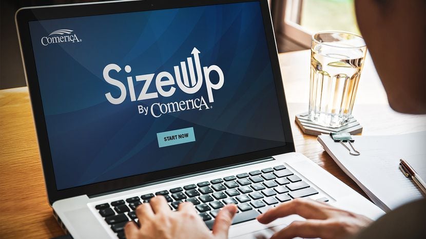 A person sits at an open laptop with the words SizeUp by Comerica on the display screen.