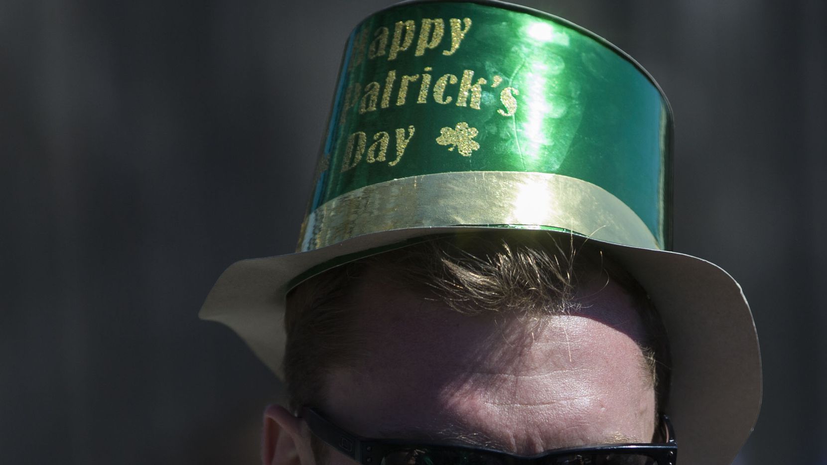A man wearing a hat that says "Happy St. Patrick's Day" during the Lower Greenville Avenue...
