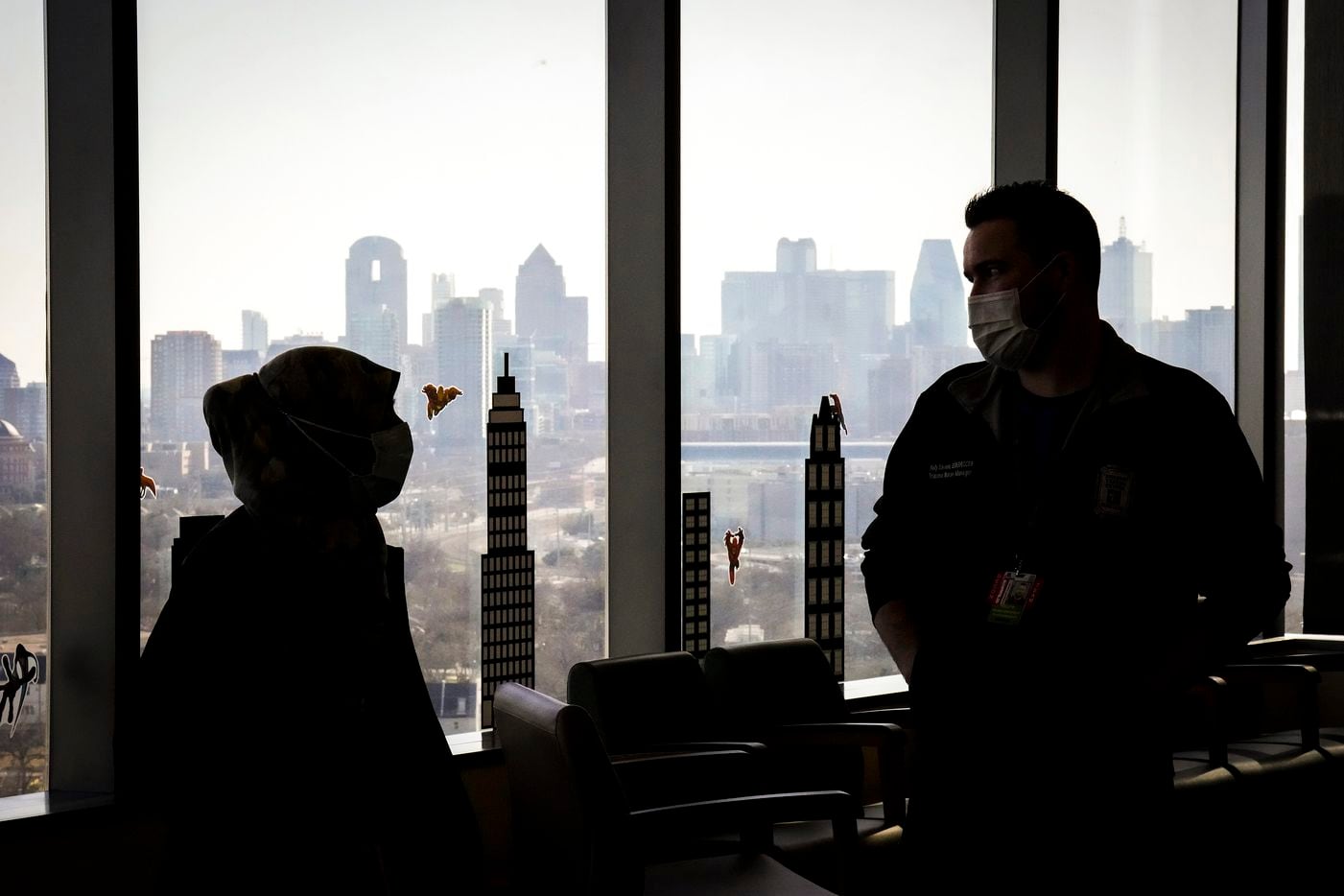 The downtown skyline is seen out the windows as nurses Kelly Stevens, unit manager in medicine services (right), and Fara Ajani, associate manager in medicine services, talk in an empty waiting area in the COVID-19 unit.