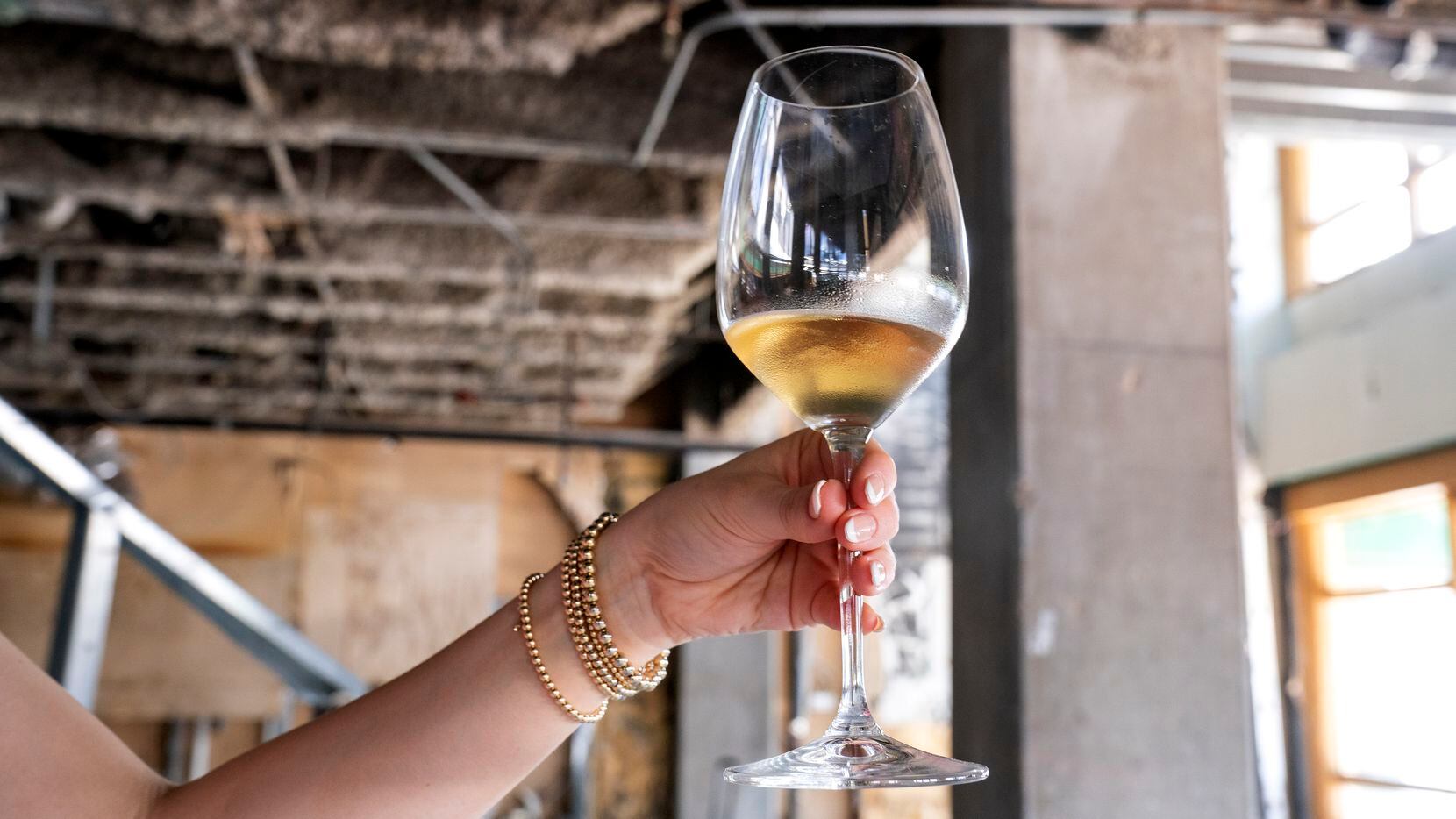 Amanda DeWitt displays a glass of wine inside the unfinished Preston Center space where she,...